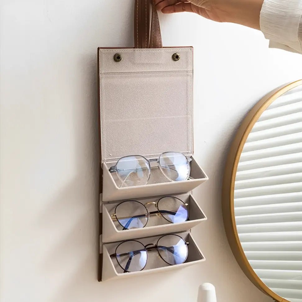 Organizador de óculos dobrável e compacto posicionado sobre mala de viagem, ideal para transporte seguro e discreto